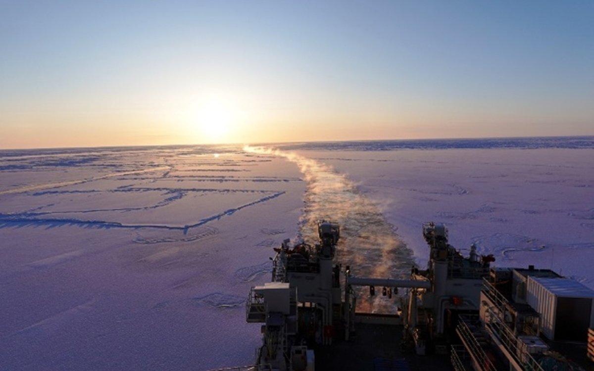Sporet til skipet er markert i isen, med solnedgang ved enden av horisonten.