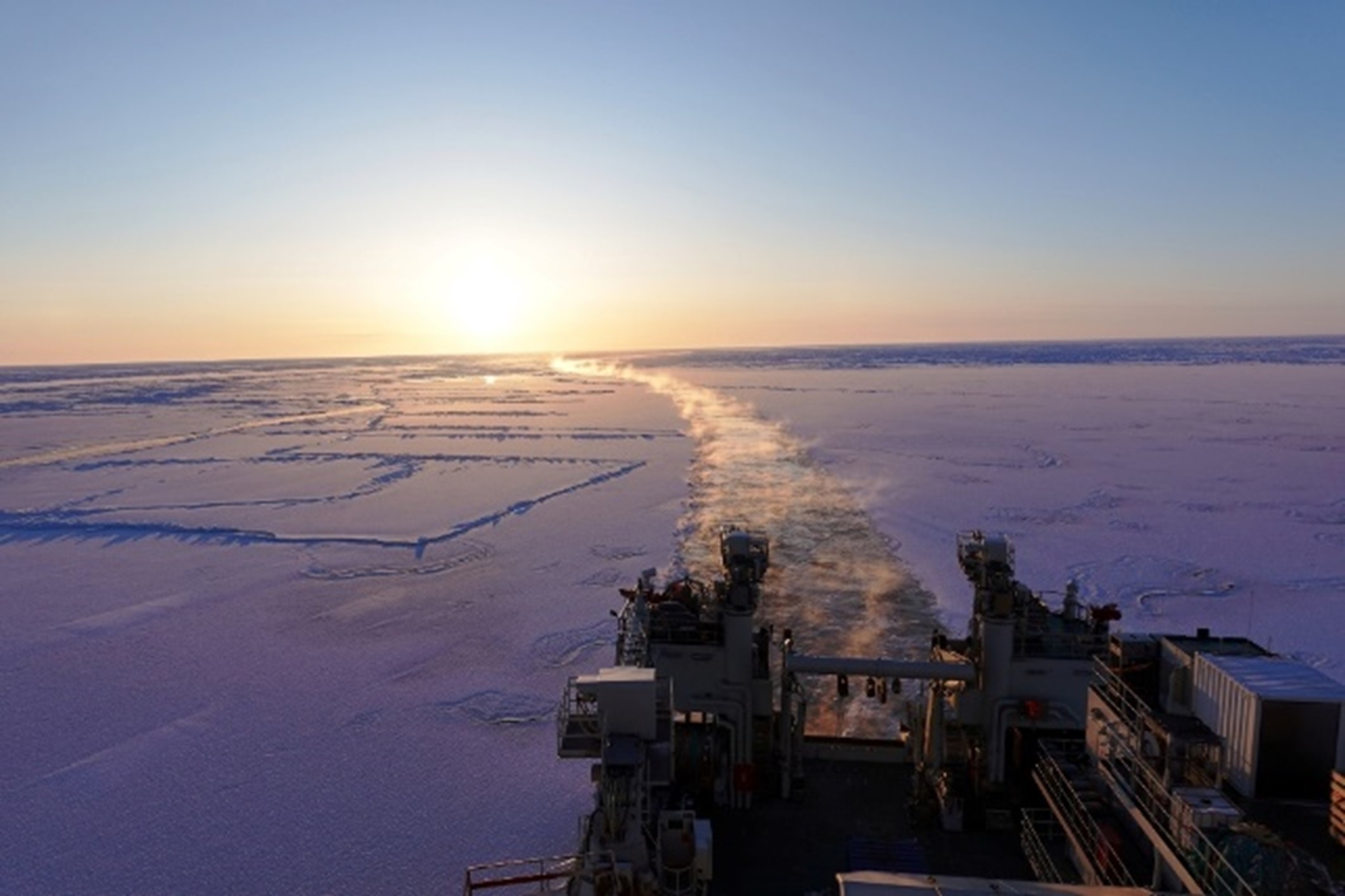 Sporet til skipet er markert i isen, med solnedgang ved enden av horisonten.