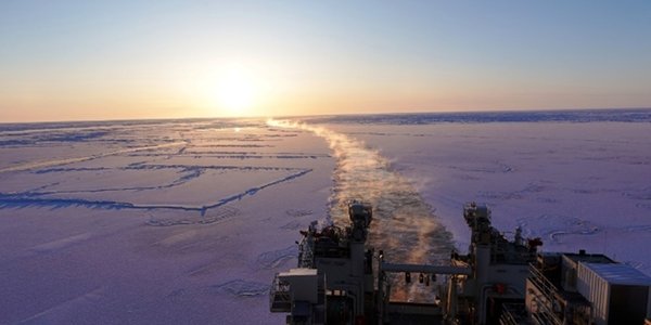 Sporet til skipet er markert i isen, med solnedgang ved enden av horisonten.