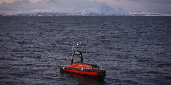 Kongsberg Discovery Sounder Unmanned Surface Vehicle (USV) in Norwegian weaters. Mountains on the horizon.