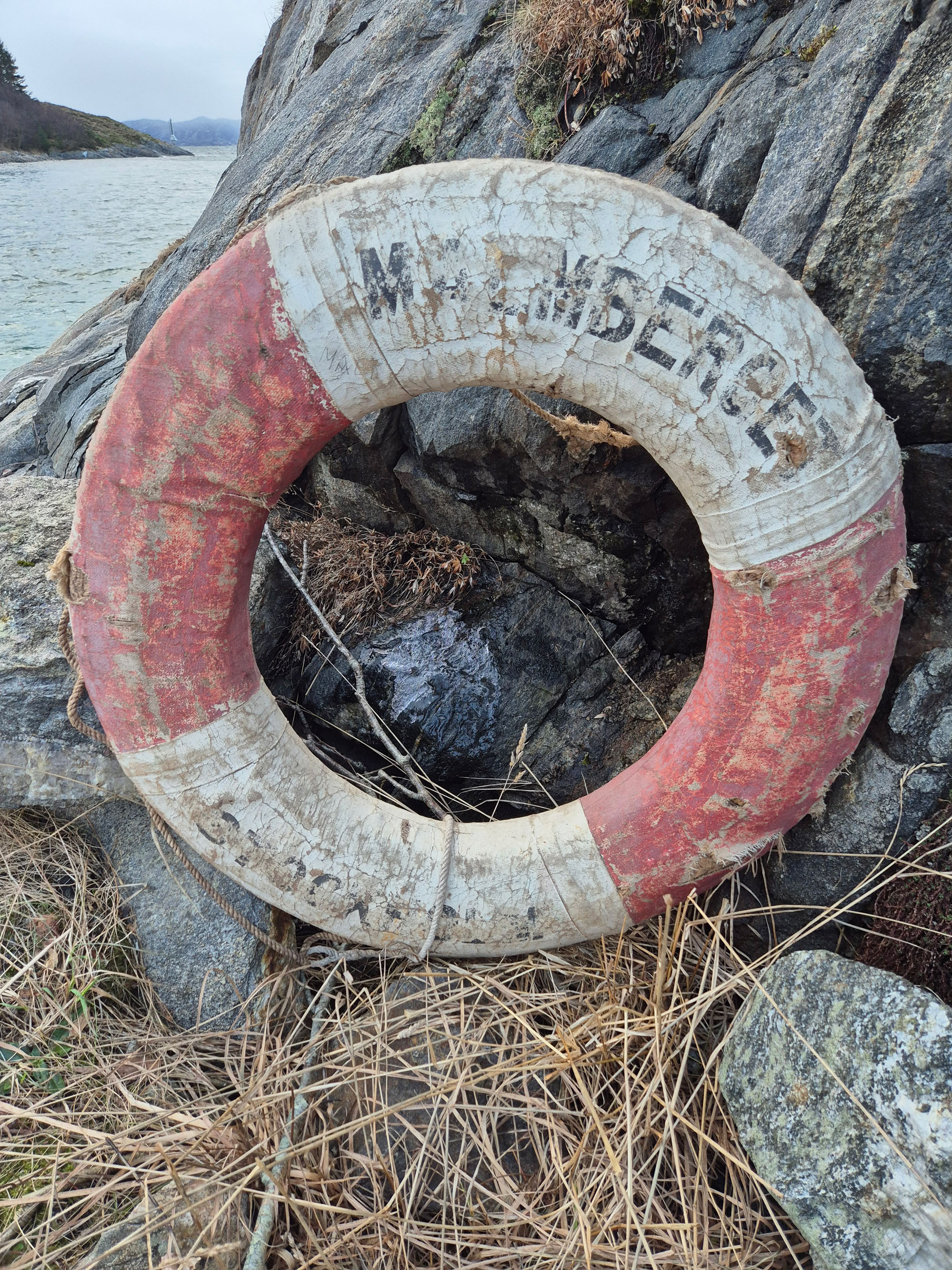 Ei rund livbøye står oppetter ein bergvegg på land.